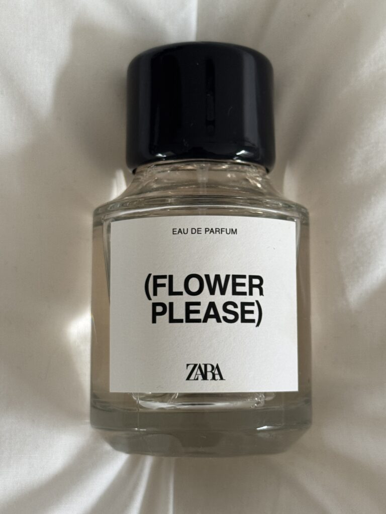 Zara Flower Please perfume bottle placed on white bedding in soft natural light
