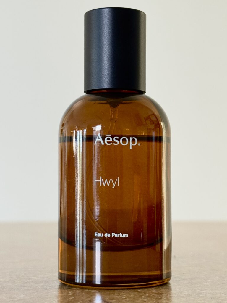 Front view of the Aesop Hwyl perfume bottle on a wooden table.