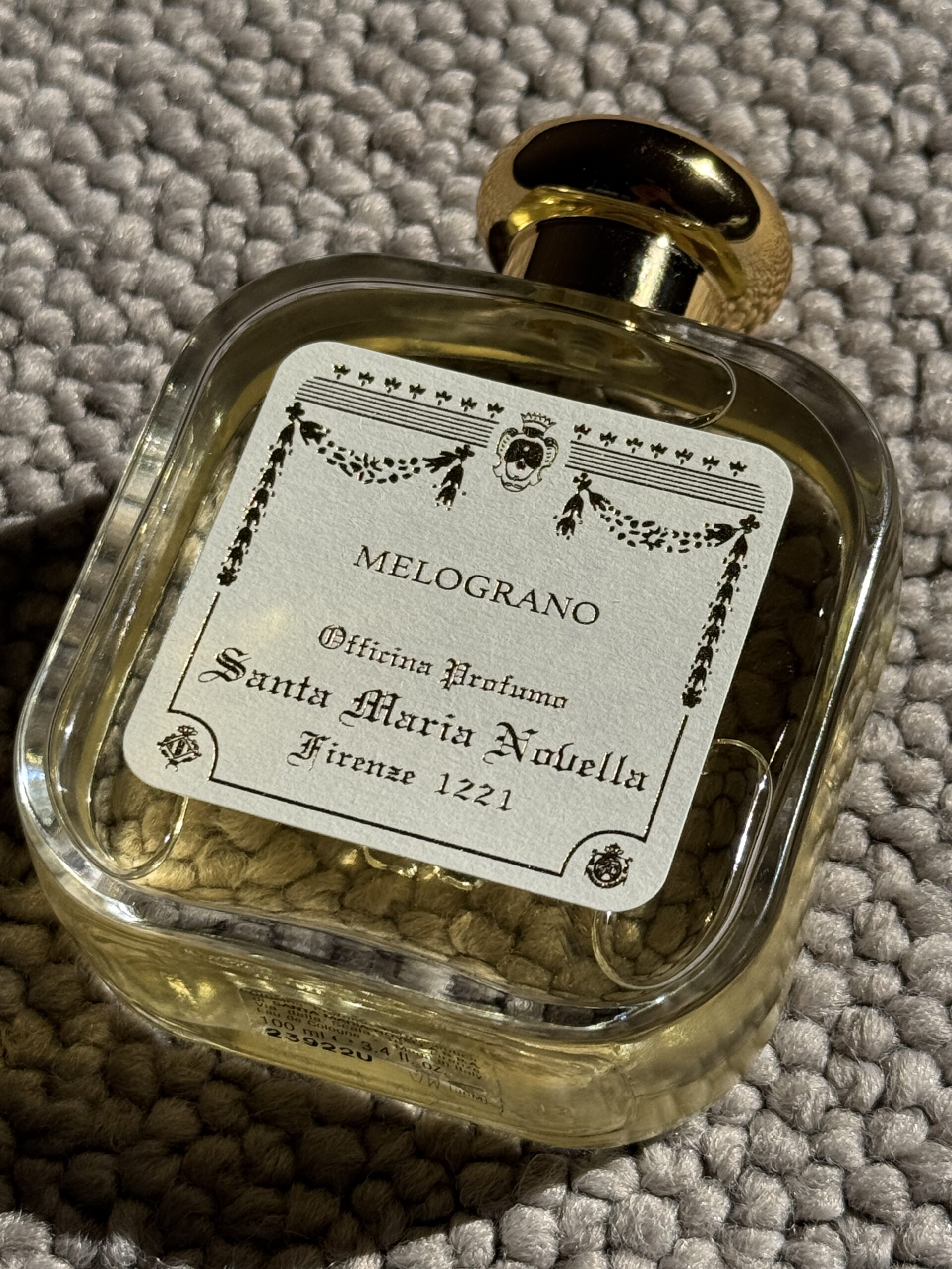 Santa Maria Novella Melograno perfume bottle on a carpet with its classic Italian elegant design